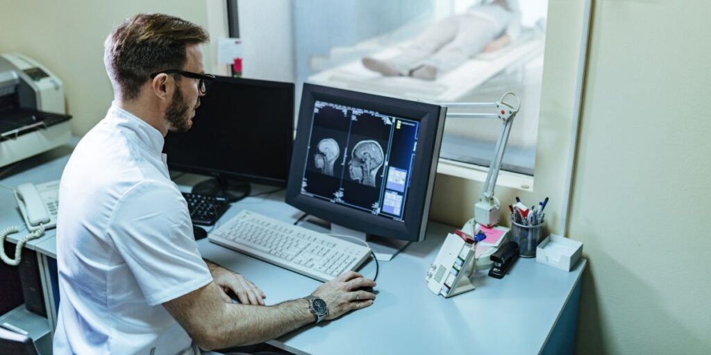 male radiologist analyzing mri scan results of a patient on computer monitor using RIS and PACS integration